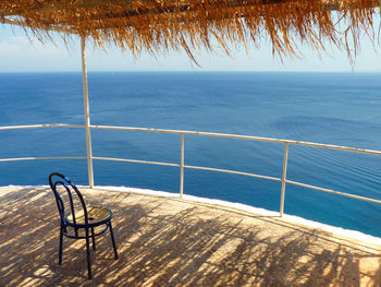 Empty chair in gazebo against sea