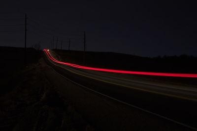 Light trails on road against sky at night