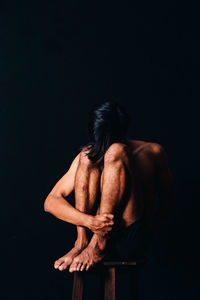 Rear view of shirtless man against black background
