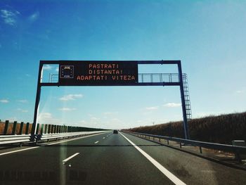 Road sign on highway against blue sky