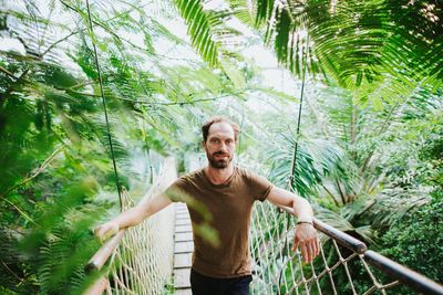 Portrait of man standing on footbridge in forest