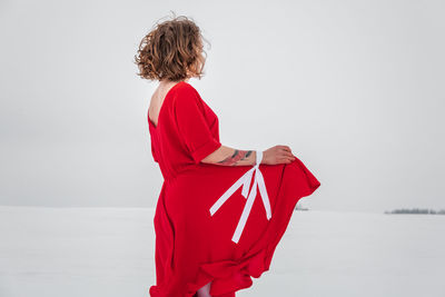 Rear view of woman standing by sea against sky