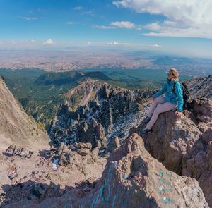 Full length of woman sitting on rock against landscape