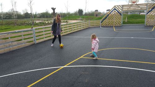 Mother and daughter playing soccer on court