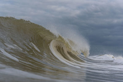 Waves splashing on shore against sky