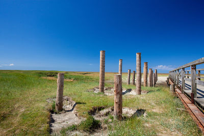 Wooden fence on field against clear blue sky