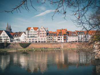 Buildings by river against sky