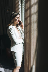 Young brunette woman business lady in white suit with mobile in the hotel room