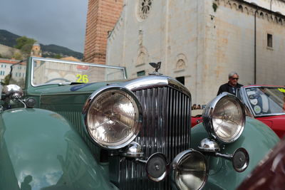 Green vintage car against historic building