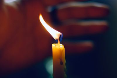 Close-up of lit candle in darkroom