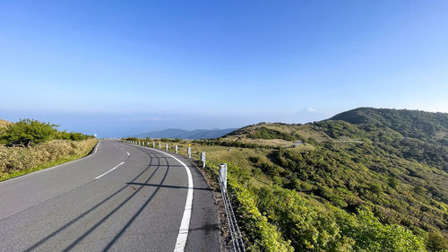 Empty road against clear blue sky