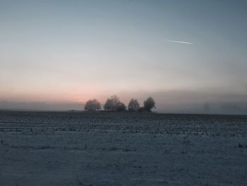 Scenic view of snow covered land against sky during sunset