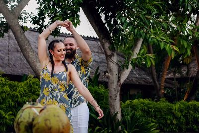 Happy woman standing by tree against plants