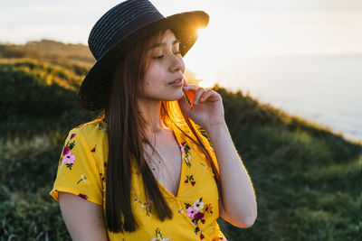 Young woman looking away while standing on field
