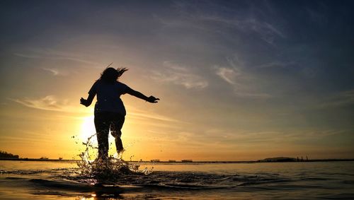 Silhouette man on beach against sky during sunset