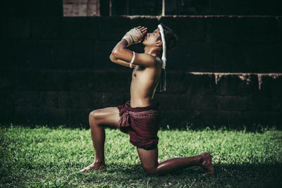 Side view of shirtless boy in grass