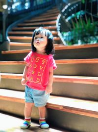 Cute girl looking away while sitting on staircase