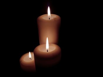 Close-up of illuminated candles in darkroom