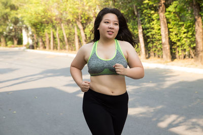 Overweight young woman running on road