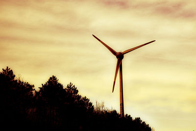 Low angle view of silhouette wind turbine against sky during sunset