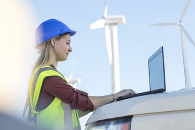 Female engineer working on wind farm, using laptop