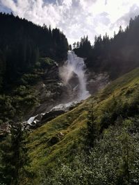 Scenic view of waterfall in forest against sky