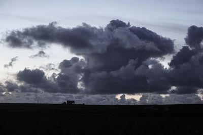 Scenic view of silhouette field against sky at sunset