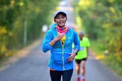 Portrait of smiling woman running on road
