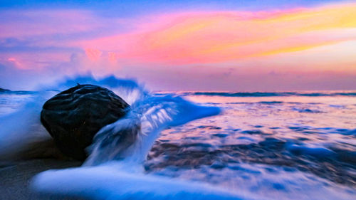 Scenic view of sea waves against sky during sunset