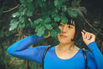 Portrait of young woman with leaves against tree