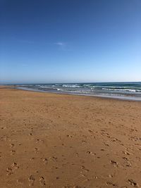 Scenic view of beach against clear blue sky