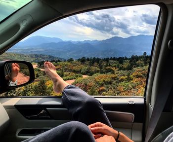 Low section of woman resting leg on car window