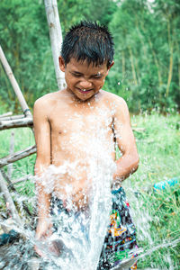 Full length of shirtless man splashing water