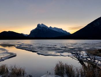 Scenic view of lake and mountains against sky during sunset