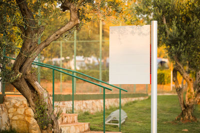 Blank signboard against trees in park