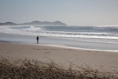 Woman standing on beach against sky