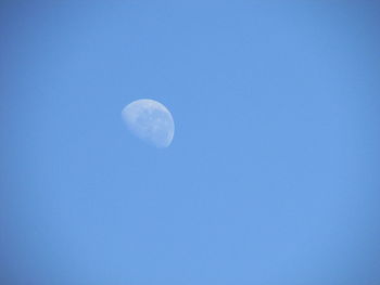 Low angle view of moon in blue sky