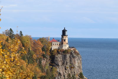 Lighthouse by sea against sky