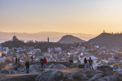 People in city against sky during sunset