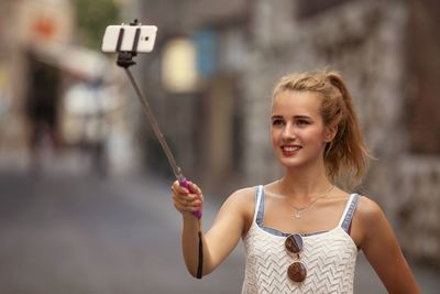 Close-up of young woman with selfie stick