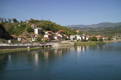 Buildings by river against clear sky