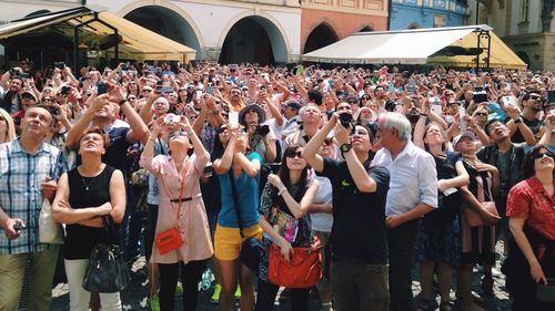 Crowd looking up and photographing outdoors