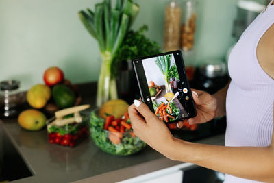 Close-up of a girl's hand taking a photo on her phone. a young woman, a culinary blogger