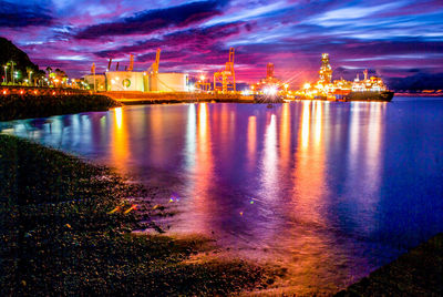 Illuminated pier over sea against sky at night