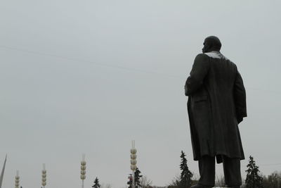 Rear view of man standing by building against clear sky