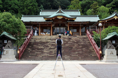 Rear view of man walking on staircase outside building