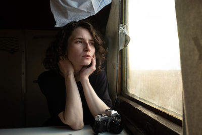 Portrait of young woman looking through window