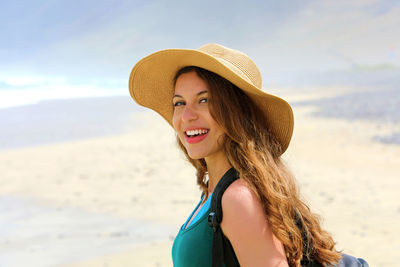 Portrait of smiling young woman wearing hat at beach