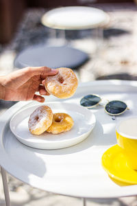 Close-up of hand holding donut  in plate