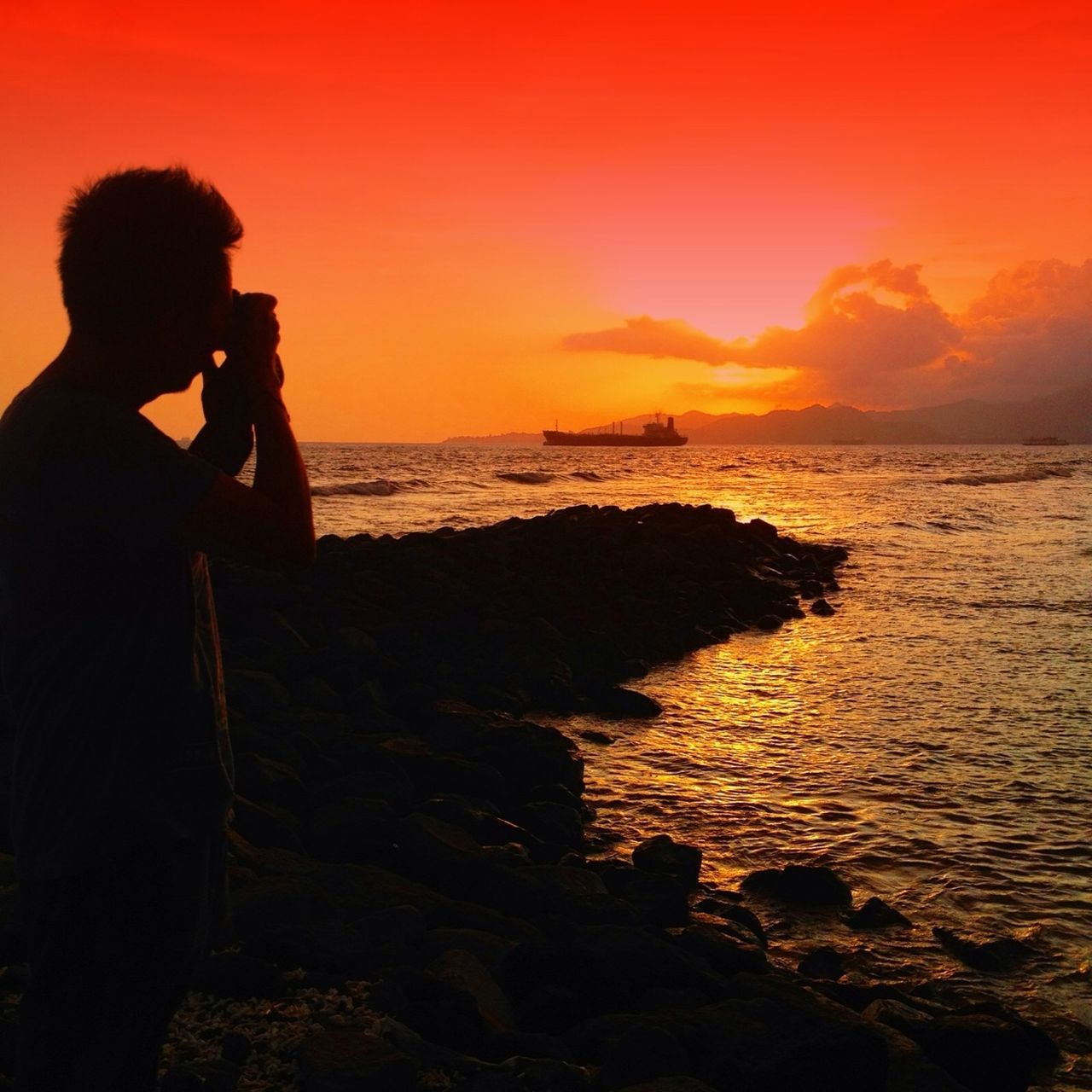 sea, sunset, horizon over water, water, lifestyles, leisure activity, silhouette, scenics, beauty in nature, sky, orange color, tranquil scene, beach, standing, tranquility, idyllic, nature, shore